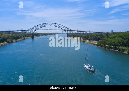 Scatto aereo di barca che passa sotto il ponte di Bourne, canale di Capo Cod Foto Stock