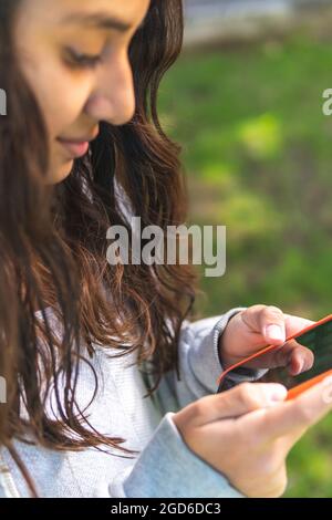 closeup delle mani di una ragazza adolescente brunette utilizzando un telefono cellulare Foto Stock
