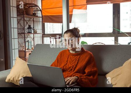 Donna caucasica che lavora attraverso il suo computer portatile mentre è seduto sul divano - lavoro da casa concetto Foto Stock