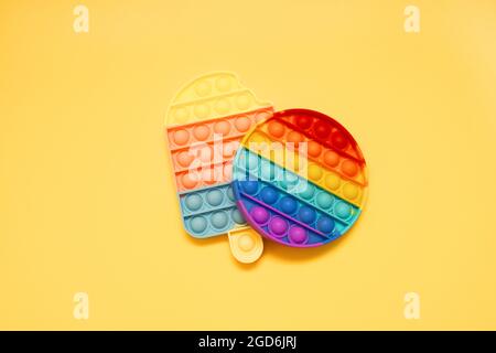 Giocattoli sensoriali colorati anti-stress pop IT per bambini su sfondo giallo Foto Stock