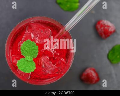 vista dall'alto del cocktail rosso con ghiaccio e foglie di menta sulla parte superiore su sfondo di pietra nera Foto Stock