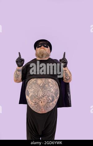 Il divertente uomo obeso in costume da eroe tiene il blaster giocattolo al  tempio su sfondo viola Foto stock - Alamy