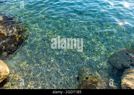 Meraviglioso mare cristallino, turchese e poco profondo con fondo in pietra e ghiaia visibile dall'alto Foto Stock