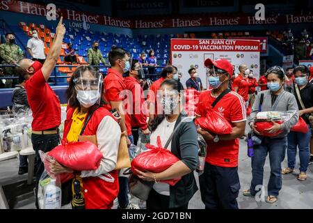 Le persone con disabilità ricevono confezioni di alimenti prima di ricevere una dose del vaccino Johnson & Johnson COVID-19 presso la Filoil Flying-V Arena di San Juan City. I funzionari filippini hanno detto che una trasmissione locale della variante delta altamente contagiosa del virus COVID-19 è stata rilevata nel paese e ha annunciato restrizioni di quarantena più severe nella capitale e un divieto di ingresso di viaggiatori provenienti da Malesia e Thailandia duramente colpiti. Metro Manila, Filippine. Foto Stock