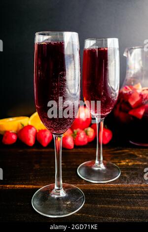 Vino Rosso Champagne Sangria servito in calici flauto: Bevande a base di vino rosso, vino frizzante, frutta fresca e serviti in bicchieri di vino Foto Stock