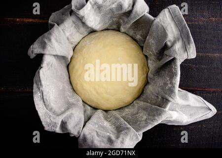 Pasta di pane francese Proving in una ciotola rivestita di lino: Pasta di pane che si erge in una ciotola di prova rivestita con un tovagliolo di stoffa Foto Stock