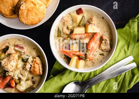 Ciotole di stufato di pollo cremoso servite con biscotti: Pollo e stufato di verdure serviti con biscotti sul lato Foto Stock