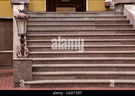 scala in marmo con scalini in pietra e lanterna in ferro forgiato in stile retrò, primo piano dell'architettura della casa con illuminazione stradale, nessuno. Foto Stock