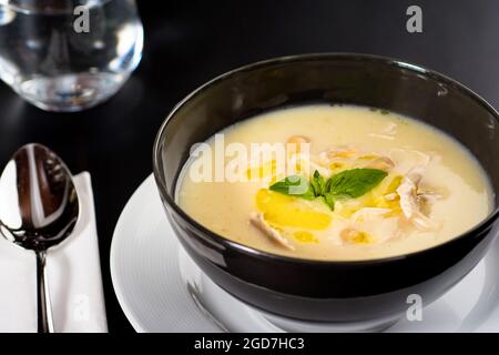 Zuppa di pollo cremosa su un piatto nero su sfondo scuro. Foto Stock
