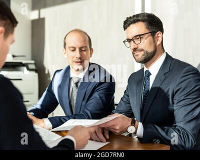 Primo piano di contratto di firma di uomo d'affari, donna che scrive la carta alla scrivania con la penna e leggendo i libri al tavolo con il documento di modulo di affari di base Foto Stock