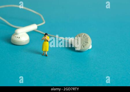 Foto di personaggi giocattolo in miniatura. Una studentessa si rilassa, sta leggendo un libro mentre ascolta la musica. Foto immagine Foto Stock