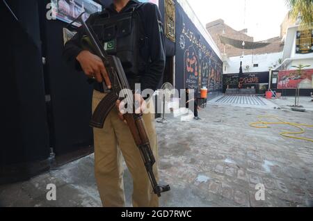 Peshawar, Pakistan. 10 agosto 2021. Un poliziotto si trova a guardia presso un Imam Bargah, una moschea musulmana sciita. I musulmani stanno osservando il mese santo di Muharram, il cui culmine è il festival di Ashura che commemora il martirio di Imam Hussein, nipote del profeta Maometto, nella città irachena di Karbala nel settimo secolo. (Foto di Hussain Ali/Pacific Press) Credit: Pacific Press Media Production Corp./Alamy Live News Foto Stock