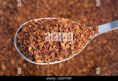 Caffè istantaneo su un cucchiaino da tè su sfondo marrone Foto Stock