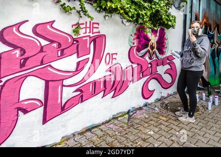 WETZLAR, GERMANIA - 23.05.2021: Giovane artista femminile facendo tipografia artificiale graffiti senico colorato sulla facciata della casa a WETZLAR; GERMANIA Foto Stock