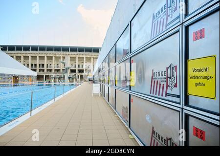 Berlino, Germania. 10 agosto 2021. Presso la piscina estiva Olympiastadion, gli stand sono coperti da tetti di protezione contro le intemperie, cartelli segnalano il rischio di ustioni. I tetti sono progettati per proteggere i supporti dalla pioggia e da ulteriori danni. Lo stadio olimpico è utilizzato come piscina all'aperto durante i mesi estivi e deve essere rinnovato. Credit: Annette Riedl/dpa/Alamy Live News Foto Stock