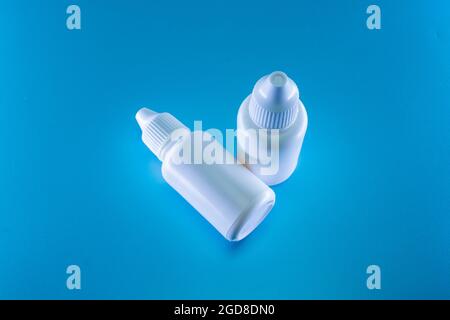 Bottiglia di gocce bianche su sfondo blu Foto Stock