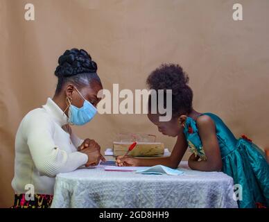 Insegnante o madre africana con maschera al naso, insegnando e aiutando una bambina con i suoi studi per eccellere nella scuola, nell'istruzione e nella carriera Foto Stock