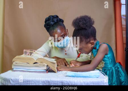 Insegnante o madre africana con maschera al naso, insegnando e aiutando una bambina con i suoi studi per eccellere nella scuola, nell'istruzione e nella carriera Foto Stock