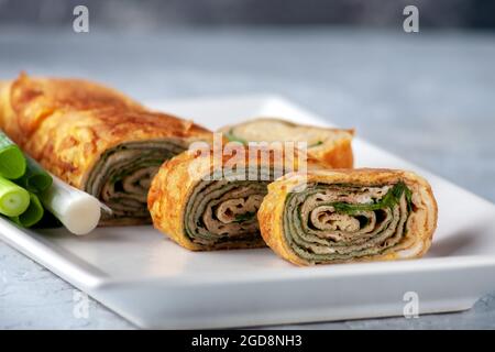 Tamagoyaki - frittata giapponese, arrotolato diversi strati di uova fritte. Cucina giapponese. Foto Stock