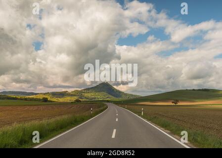 Strada di campagna nel paesaggio vulcanico Hegau con vista sul Hohenhewen, quartiere di Costanza, Baden-Wuerttemberg, Germania Foto Stock