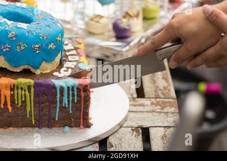 Una colorata torta a due strati, con vivaci gocce di glassa e una ciambella blu sulla parte superiore, perfetta per una festa. Foto Stock