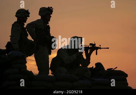 Tre soldati dell'esercito degli Stati Uniti (USA) della 101esima divisione aerea, uno armato con una carabina M4 Colt da 5,56 mm dotata del sistema di armi modulari Knights Armament Company (KAC) (MWS), osservano il movimento dalla cima di una posizione bunker fortificata a Kandahar, Aeroporto Internazionale, Afghanistan, durante l'operazione CHE PERENNE LA LIBERTÀ. (FOTO US NAVY DI PH1 TED BANKS 020121-N-3236B-012) Foto Stock