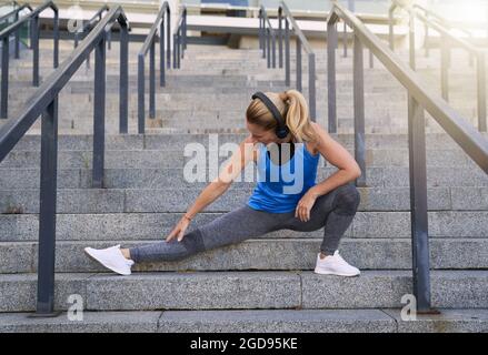 Indossa le cuffie che allungano le gambe mentre ti alleni all'aperto in città Foto Stock