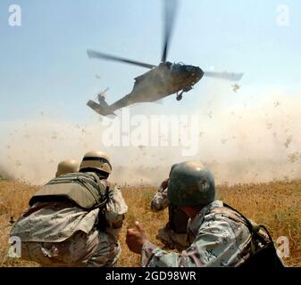 Soldati dell'esercito iracheno del 3° Battaglione (BN) 3° Brigata (BDE) 5° Divisione dell'esercito iracheno (IAD) si stringono e si preparano ad avvicinarsi ad un elicottero dell'esercito statunitense (USA) UH-60 Blackhawk (Black Hawk) che li trasferirà da un villaggio vicino a Mujahida City, Iraq (IRQ). (FOTO BLU MARINO DI MC1 JACKEY BRATT 060816-N-4097B-032) Foto Stock