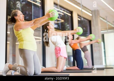 Maturo femmina esecuzione serie di esercizi con pilates palla Foto Stock