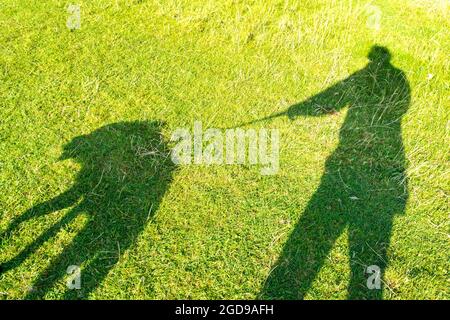 Batheaston, Inghilterra, tempo del Regno Unito. 12 agosto 2021. Ombra di un cane camminatore su Little Solsbury Hill in una bella mattina di sole. Credit: Richard Wayman/Alamy Live News Foto Stock