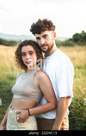 Bella coppia eterosessuale in un campo d'erba a piedi e baciare Foto Stock