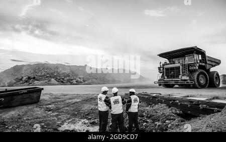 JOHANNESBURG, SUDAFRICA - 06 gennaio 2021: Una vista posteriore di tre uomini che guardano ad un camion grande di scarico che trasporta i minerali di platino in Sudafrica Foto Stock