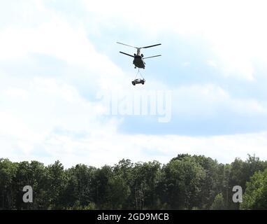 Un elicottero CH-47 Chinook solleva gli alberi dopo che i soldati del 1° Battaglione, 109° Reggimento fanteria, 2° Team di combattimento Brigata Fanteria, hanno agganciato un veicolo a ruote multiuso ad alta mobilità durante l'allenamento con carico di imbragatura a Fort Indiantown Gap, Pa., il 4 agosto 2021. L'addestramento del carico di imbracatura ha permesso ai soldati dal battaglione di diventare più esperti con il tipo di abilità che avrebbero imparato in Air Assault e Pathfinder School (U.S.A. Foto dell'esercito di Sgt. 1° classe Matthew Keeler) Foto Stock