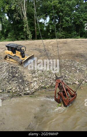 Gli operatori di attrezzature pesanti del corpo degli ingegneri dell'esercito degli Stati Uniti, Memphis District Clearing & Snagging Unit, sono i primi team in un'area a prepararla per l'infrastruttura di revisione necessaria per mantenere l'integrità del canale lungo il fiume Mississippi e i suoi principali affluenti. Il team si affida a attrezzature pesanti come questa gru e la benna (a destra), con la sua capacità di sollevamento di 120 tonnellate, per eliminare la vegetazione e i detriti durante la stagione di 8 mesi che va da luglio a marzo. Foto Stock