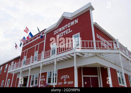 Il rosso, legno Downtown Hotel a Dawson City, Yukon, Canada durante una giornata nuvolosa, coperto di bandiere. Foto Stock