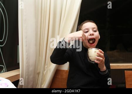 Ragazzo che mangia tiramisù in vetro nel ristorante Foto Stock