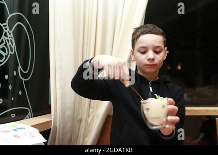 Bambino che mangia tiramisù in vetro nel ristorante Foto Stock