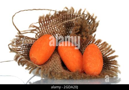 Tre mini carote dolci arancioni con un tovagliolo di iuta, primo piano, su sfondo bianco. Foto Stock