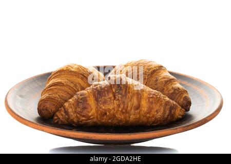 Tre fragranti croissant con ripieno di cioccolato su un piatto di ceramica, primo piano, isolati su bianco. Foto Stock