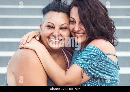 Due sorelle gemelle adulte abbracciano. Stili diversi Foto Stock