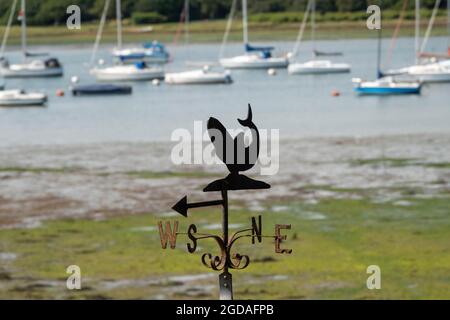 Whale Weathervane uno strumento utilizzato per mostrare la direzione del vento con uno sfondo sfocato di barche e acqua Foto Stock