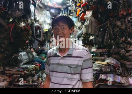 Phnom Penh, Cambogia - 31 dicembre 2016: Un fornitore di parti di ricambio che guarda la macchina fotografica nel suo negozio al mercato russo Foto Stock