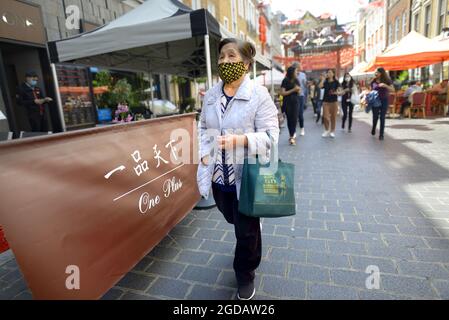 Londra, Inghilterra, Regno Unito. Anziana signora in Gerrard Street, Chinatown, indossando un facemask durante COVID, luglio 2021 Foto Stock