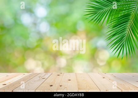 Tavolo vuoto in legno e foglia verde di palma bokeh Foto Stock