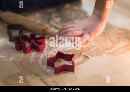 Le mani dei bambini fanno i biscotti di Capodanno dello zenzero.Preparazioni per Natale Foto Stock