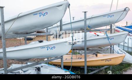 Laser Pico's, piccole barche a vela accatastate vicino al lungomare. Foto Stock