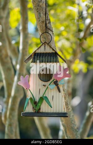 Primo piano di casa di uccelli decorata con fiori rosa. Foto Stock