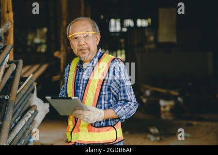 Ritratto il caposquadra di lavoro di un ingegnere anziano intelligente che utilizza la tecnologia dei computer tablet in cantiere. Foto Stock