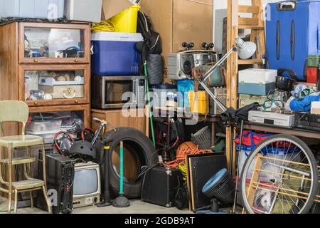 Hoarder ammasso e roba di rifiuto della famiglia che affollano l'angolo di un garage suburbano suburbano suburbano disy. Foto Stock