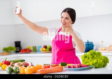 Foto ritratto donna in grembiule cottura selfie taling mostrando come segno Foto Stock